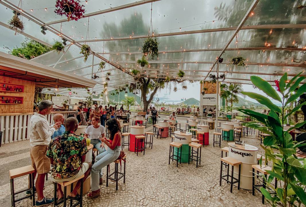 A imagem mostra um bar com mobiliário de madeira e colorido e espaço a céu aberto