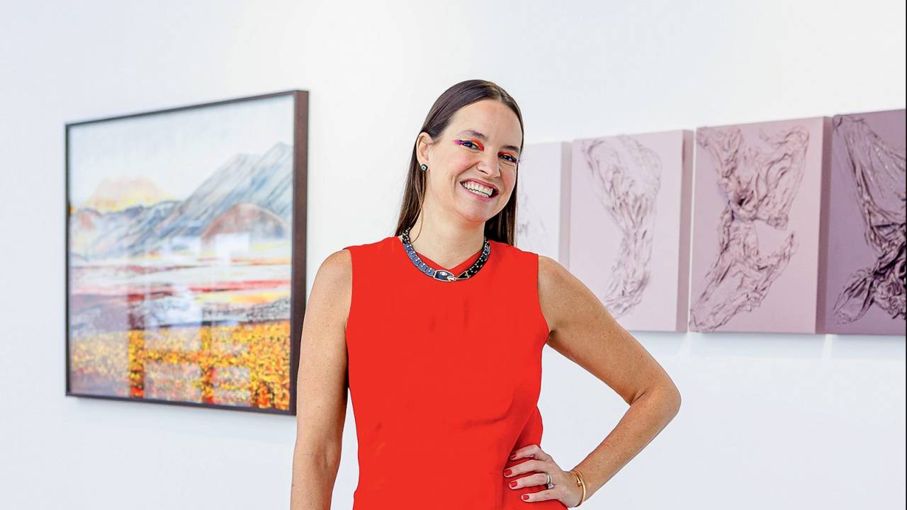 Brenda Valansi com a mão na cintura. Atrás dela, quadros de arte contemporânea