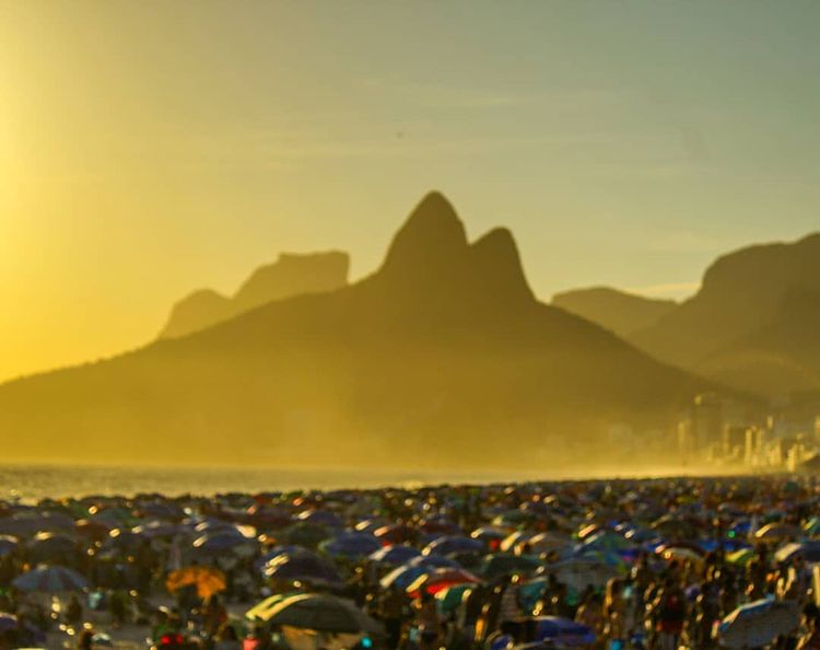 A imagem mostra um dia ensolarado com as areais lotadas de guarda-sóis