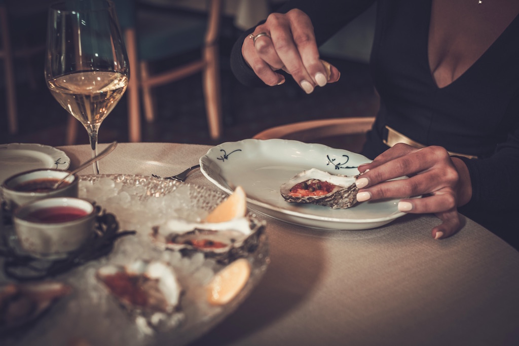 Woman eating oysters in a restaurant.