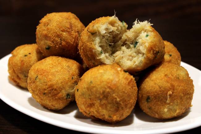 A imagem mostra um monte de bolinhos de bacalhau, alguns deles abertos