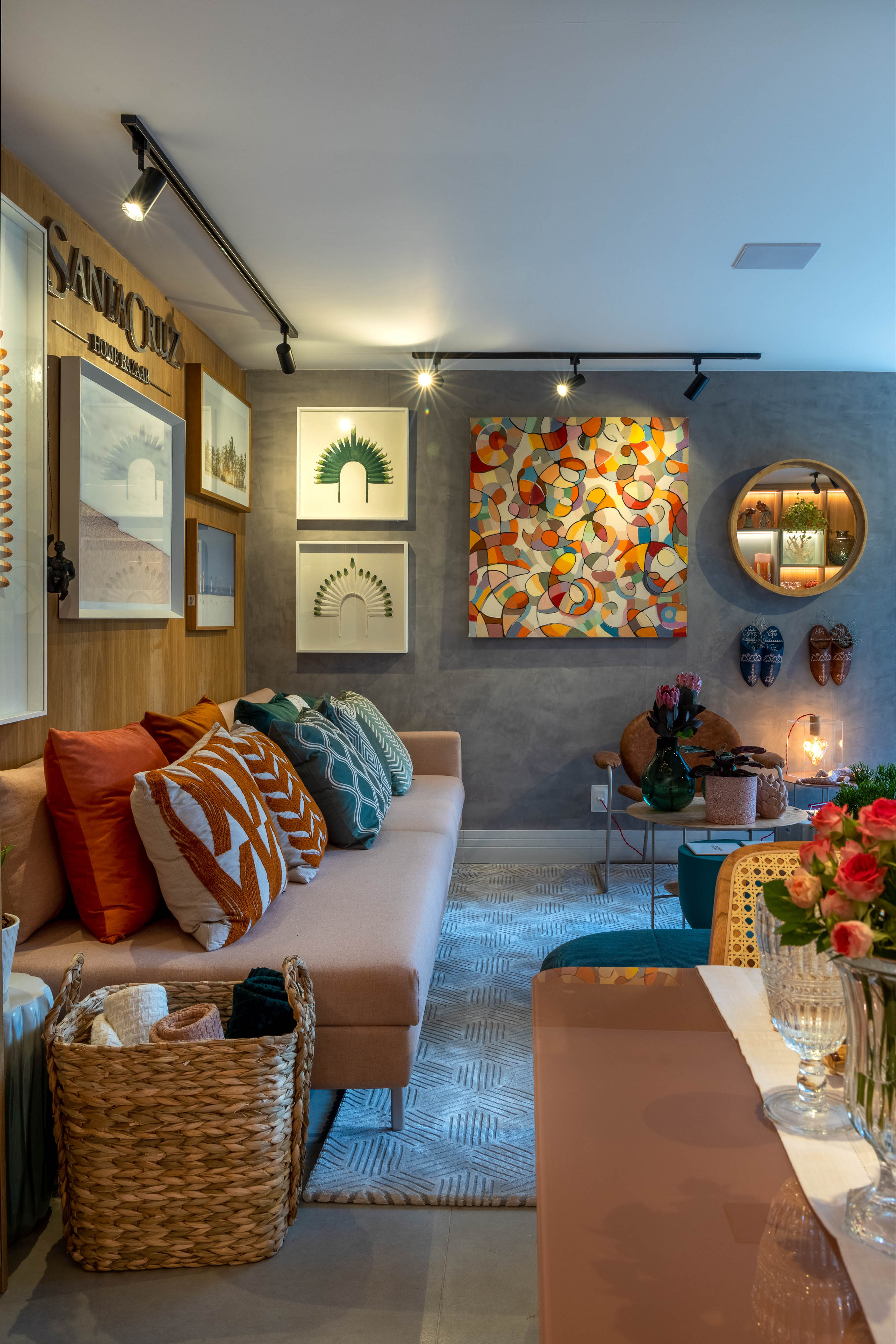 Sala de estar com quadros coloridos, sof&aacute;s em tons de rosa e almofadas coloridas