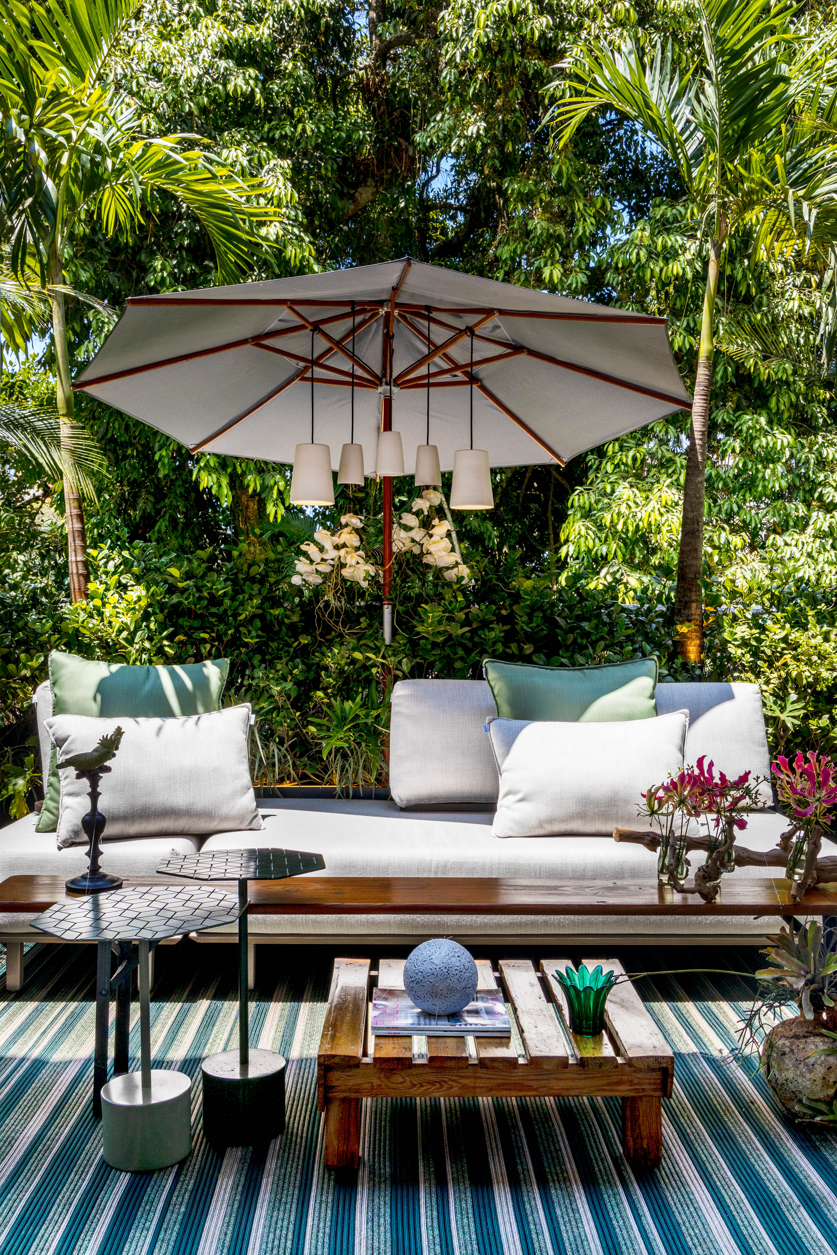 Varanda da Casacor de 2021 com um grande sof&aacute; e ombrelone