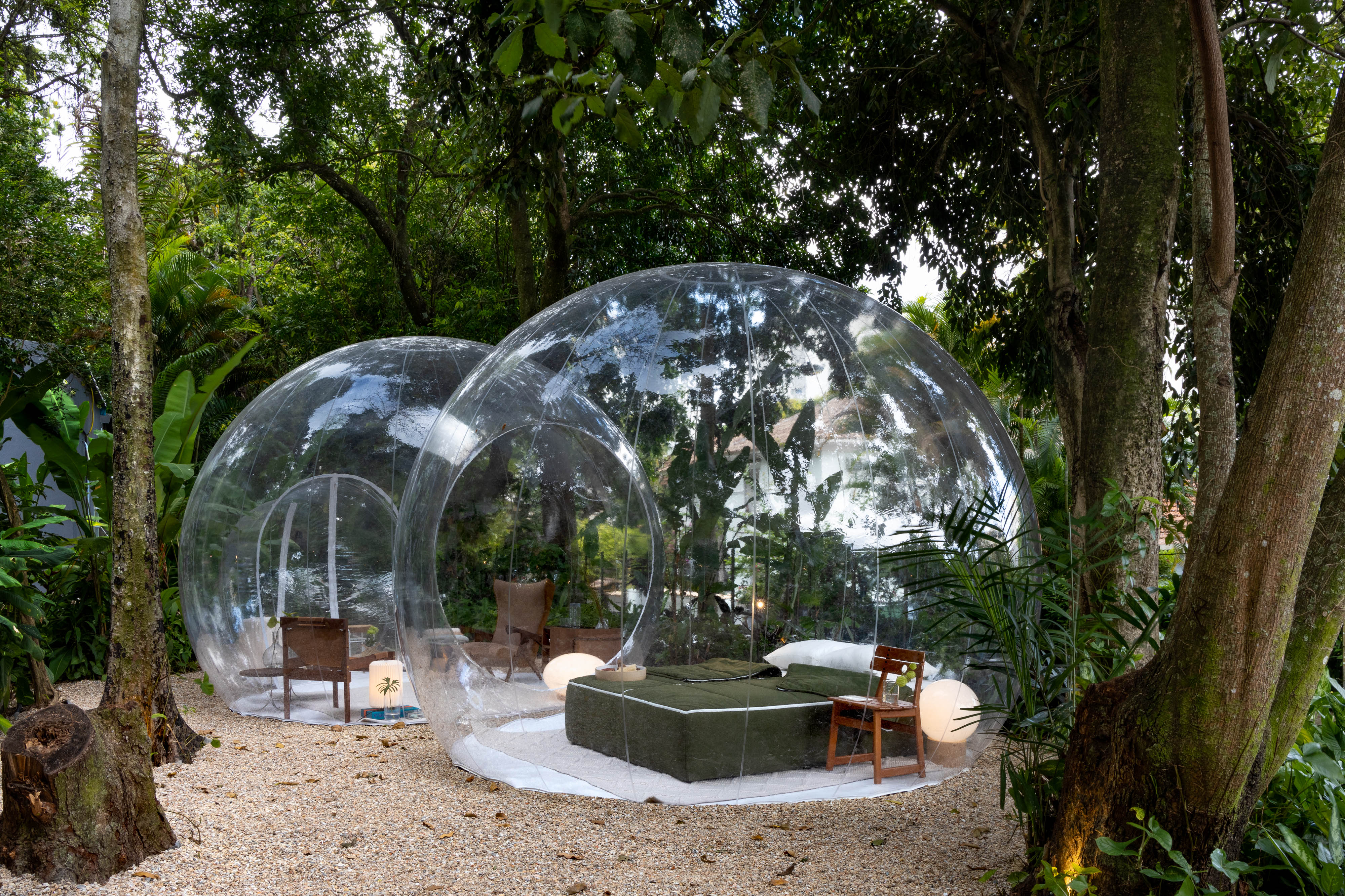 Bolha gigante no meio do jardim com cama e poltronas dentro dela