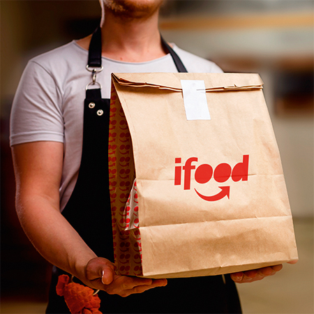 Ifood pessoa segurando uma embalagem de entrega do iFood