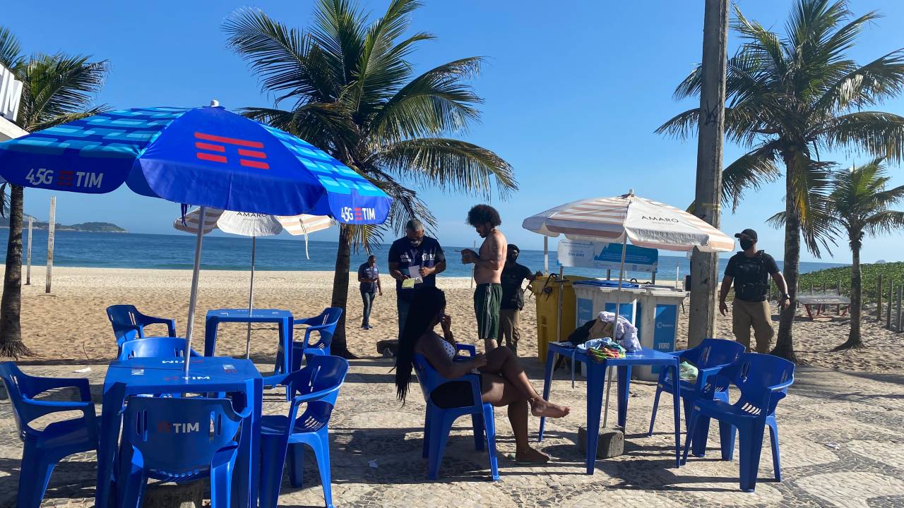 A imagem mostra um banhista sendo multado por guardas municipais em Ipanema
