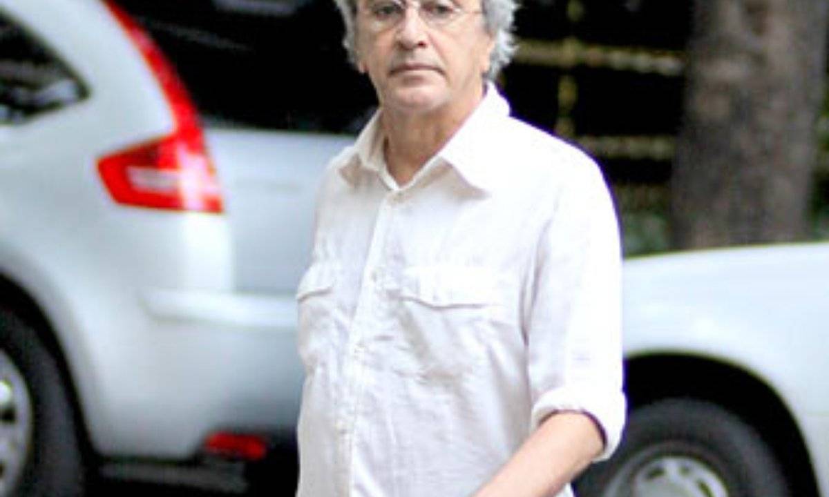 A imagem mostra Caetano Veloso andando por uma rua do Leblon