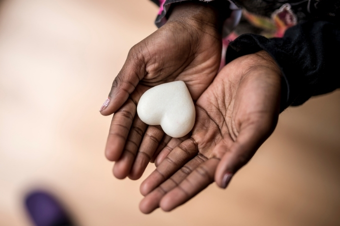 Mão de menina negra segurando um coração branco de porcelana