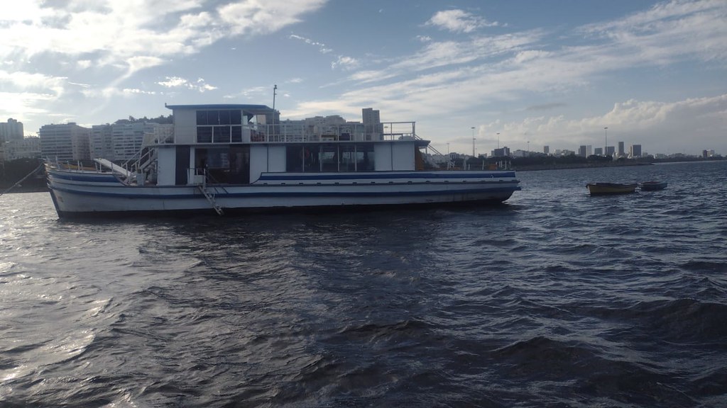A imagem mostra um barco, ancorado no mar da Urca