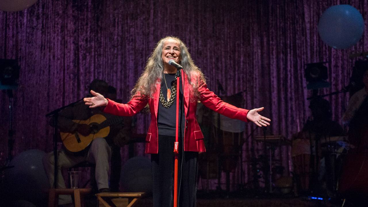 Maria Bethânia no palco, com os braços abertos