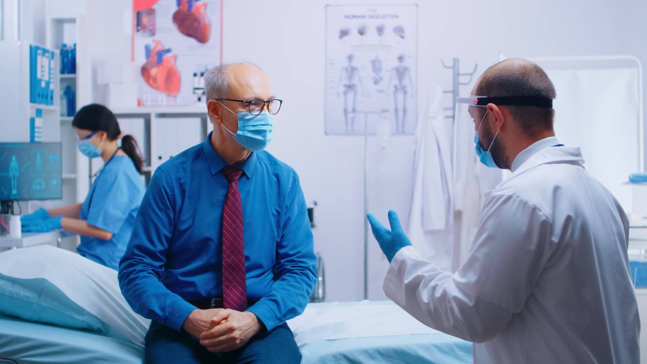 Médico atende um paciente sentado na maca.