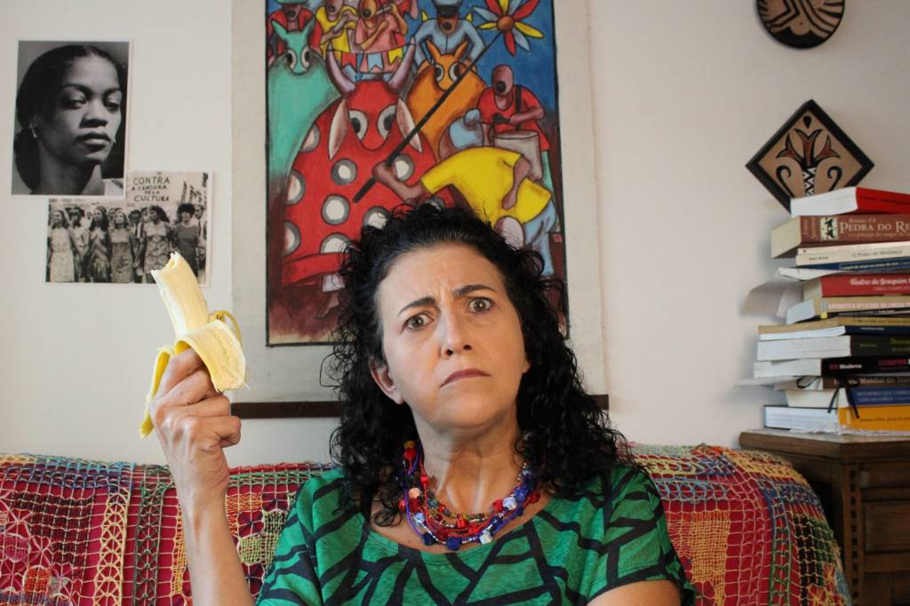 Conselho de Classe Atriz Dárdana Rangel 2 Atriz sentada no sofá comendo banana