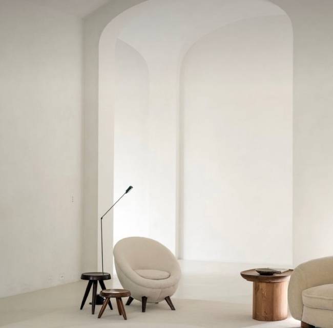 Estilo escandinavo A imagem mostra uma sala com uma poltrona, banquinhos e uma luminária de piso