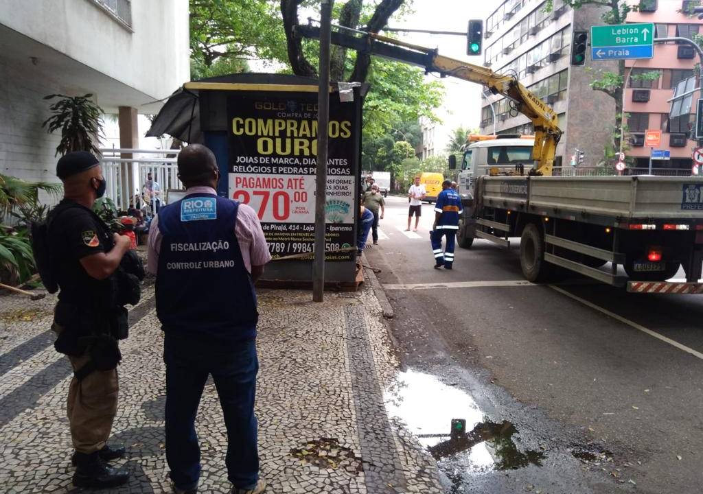 Foto mostra banca de jornal sendo demolida