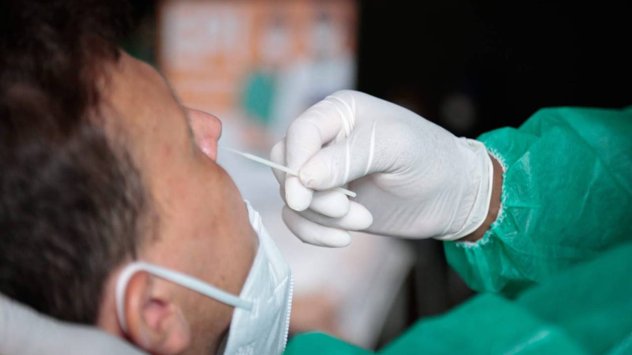 Foto mostra profissional de saúde fazendo teste de covid em paciente
