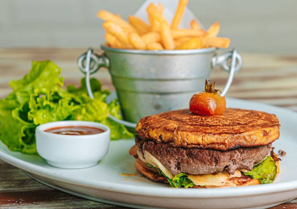 Foto mostra smash burguer acompanhado de salada e fritas