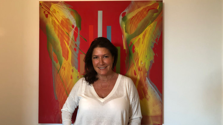 LolaDuran Lola Durán Úcar é branca, de cabelos castanhos e lisos, e está de blusa branca de manga comprida. Ao fundo, um quadro abstrato em que predominam as cores vermelha e amarela.