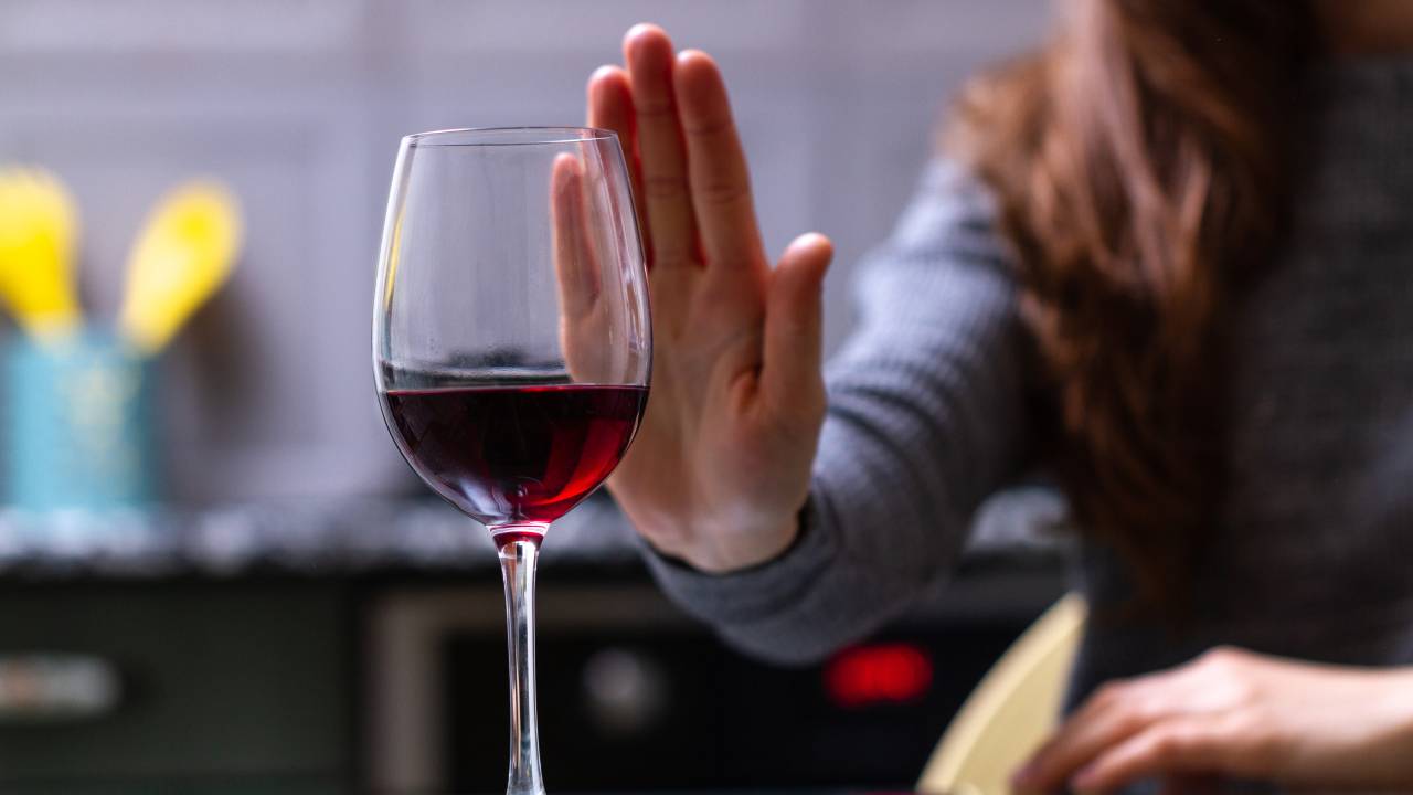 Mulher recusa uma taça de vinho.