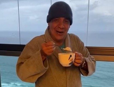 Zeca Pagodinho de roupão e pote com canjica e colher.