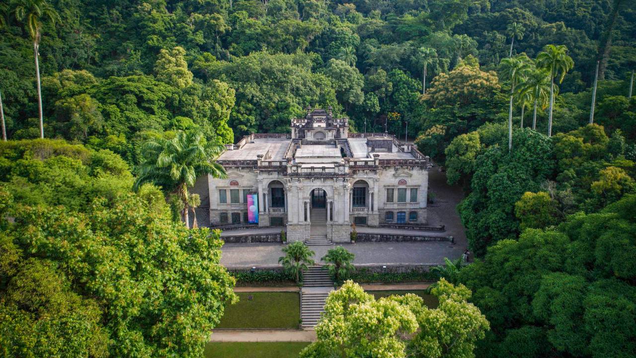 Foto área da frente do palacete Parque Lage, com o espaço cercado pela Mata Atlântica.