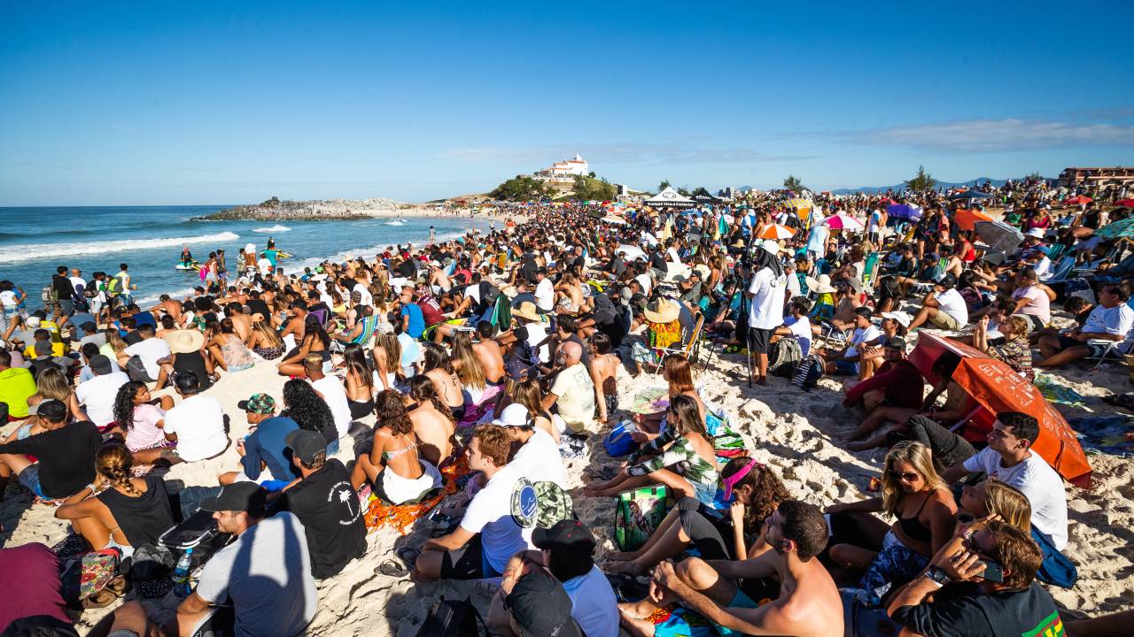 Foto mostra praia cheia em campeonato de surfe