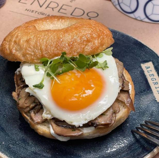 Bagel do Enredo: com recheio de cream cheese temperado, ovo e cogumelos shiitake e paris salteados na manteiga Bagel do Enredo: com recheio de cream cheese temperado, ovo e cogumelos shiitake e paris salteados na manteiga