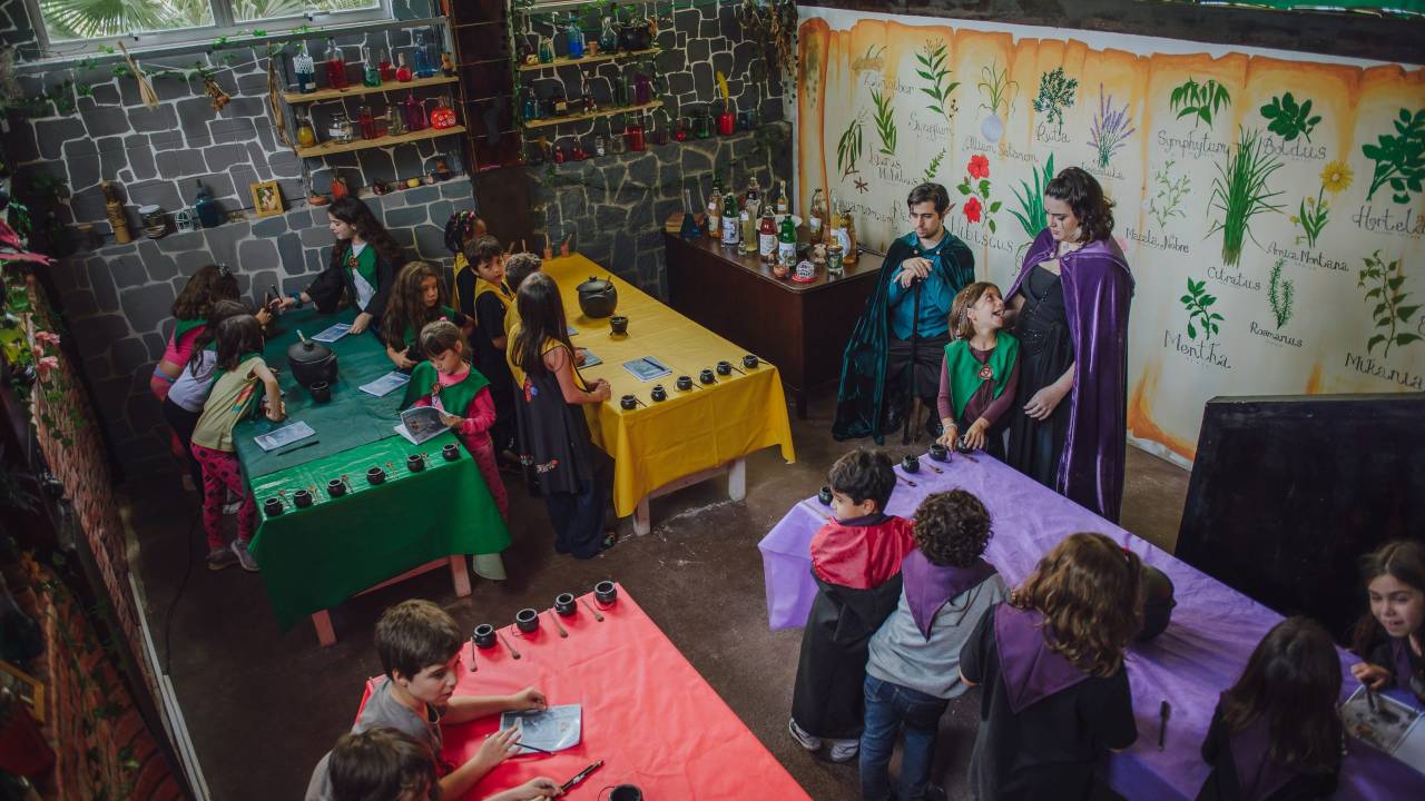 Foto mostra crianças tendo aula sobre magia em colônia de férias