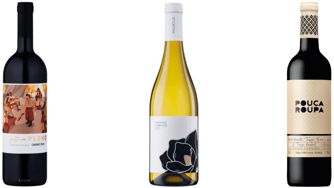 Tr&ecirc;s garrafas de vinho em fundo branco: uma de tinto com r&oacute;tulo ilustrado de pessoas dan&ccedil;ando, uma de branco com flor preta no r&oacute;tulo, e outra de tinto com r&oacute;tulo bege escrito Pouca Roupa